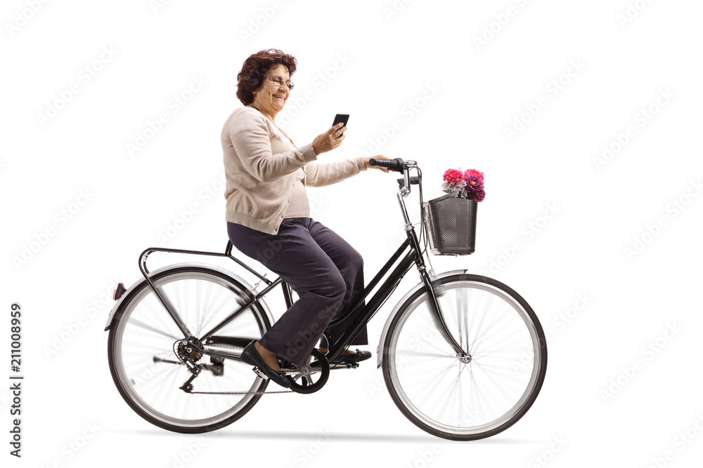 Elderly woman riding a bicycle and looking at her phone Elderly woman riding a bicycle and looking at her phone