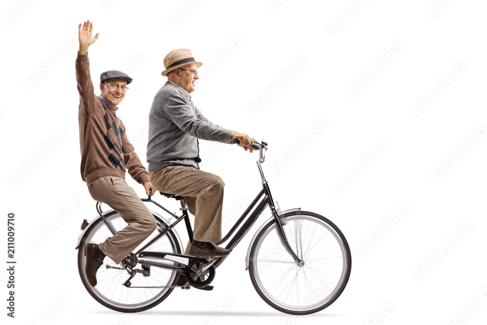Seniors riding on a bicycle with one of them waving at the camera Seniors riding on a bicycle with one of them waving at the camera