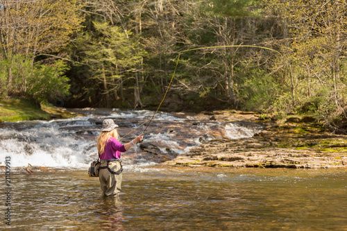 Senior Woman Casting Fly Fishing Rod in the River