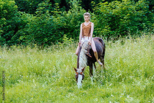 Beautiful woman on a horse. Horseback rider on summer meadow, green backgound. Riding lesson and leisure concept.
