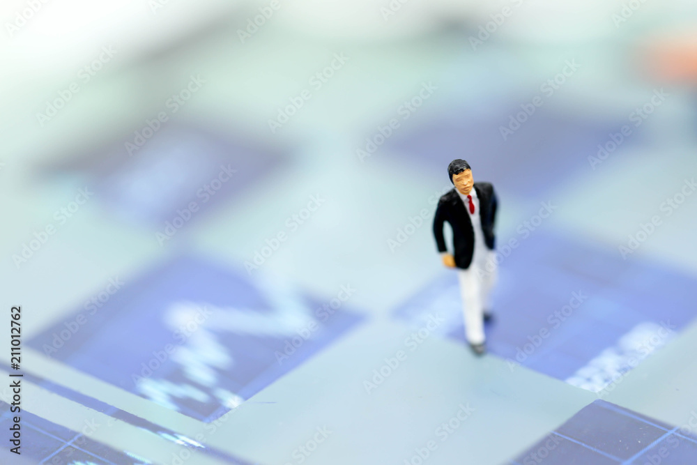 Miniature people : Businessman standing on a graph chart financial analysis review document Miniature people : Businessman standing on a graph chart financial analysis review document