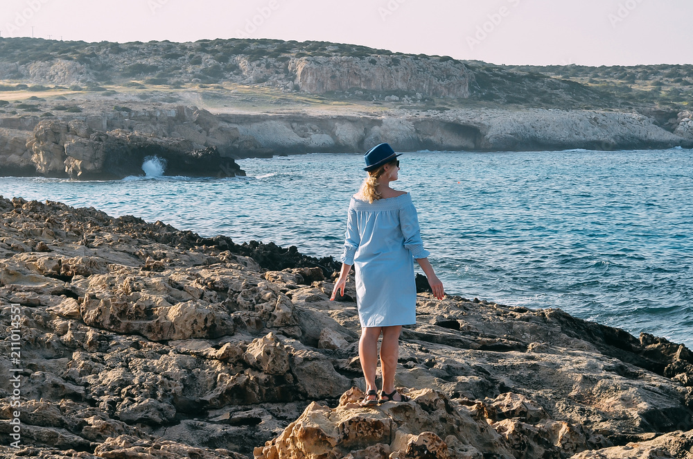 Beautiful young woman standing near sea. Young caucasian female model near sea. Woman onmountain in Cyprus, Mediterranean Sea