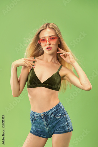 Cute girl in swimsuit posing at studio. Summer portrait caucasian teenager on green background.