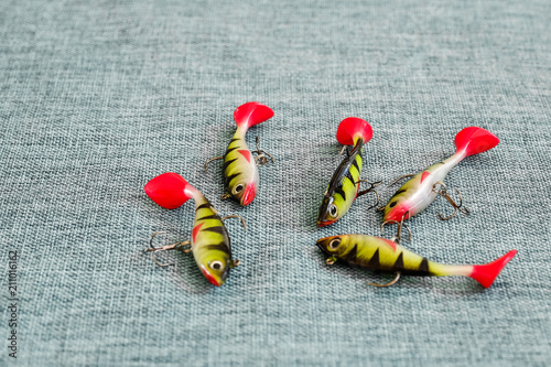 Silicone bait. Twisters on the background of burlap. Lures with treble hooks in the form of small perch.