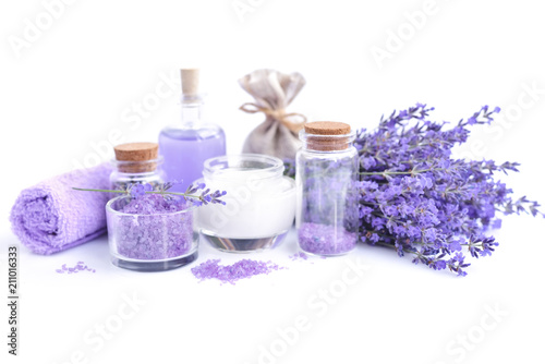 Spa composition with flowers of lavender, cream, salt and bottle of essential oil on a white background