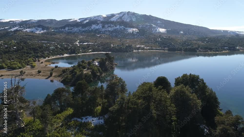 Aerial drone scene of Alumine lake, in Villa Pehuenia, Moquehue, Neuquen, Patagonia Argentina. Camera passing over an islands to the coast. Mountains with snow and low clouds. Aerial drone scene of Alumine lake, in Villa Pehuenia, Moquehue, Neuquen, Patagonia Argentina. Camera passing over an islands to the coast. Mountains with snow and low clouds.