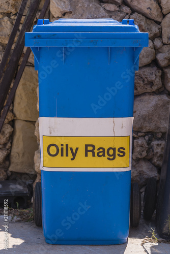 Blue bin with a sign on it for oily rags. © Stephen