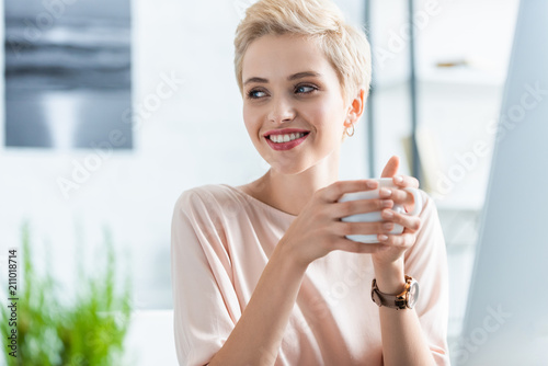 portrait of woman holding cup of coffee and looking away