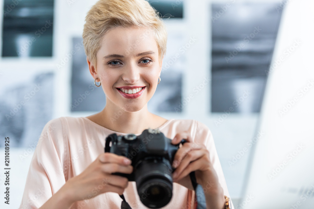 portrait of smiling female photographer holding photo camera