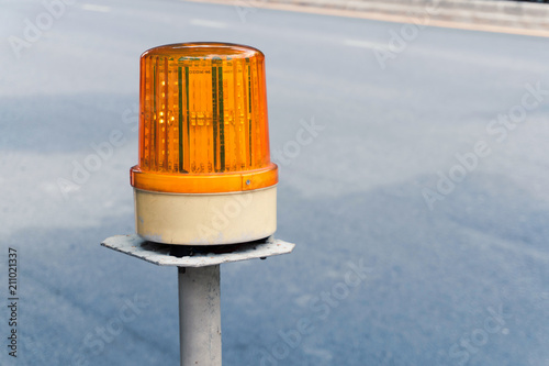 close up of a yellow LED warning light on the white metal pole beside the street