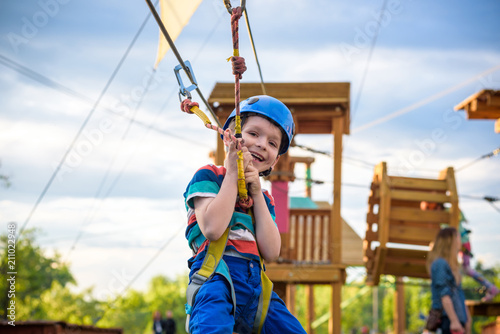 Little cute boy enjoying activity in a climbing adventure park on a summer sunny day. toddler climbing in a rope playground structure.