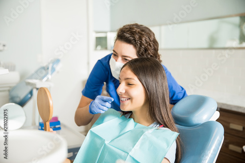 Dentist Showing Braces To Teenage Girl In Mirror At Clinic photo