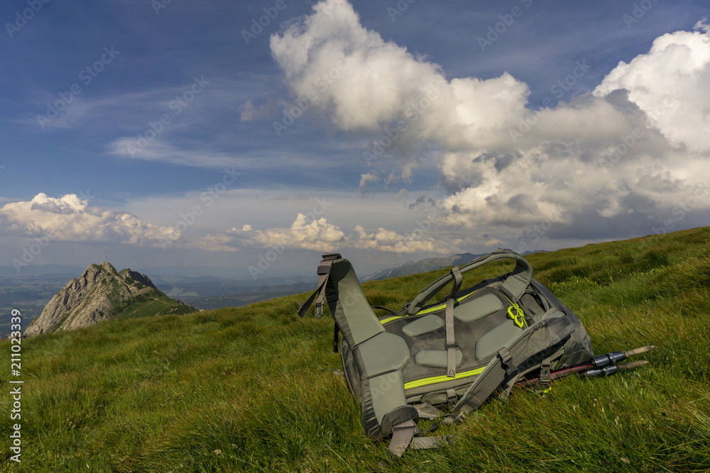 Backpack on green grass against the background of mountains and sky. Backpack on green grass against the background of mountains and sky.