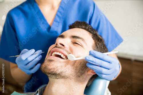 Man Receiving Treatment From Dentist In Dental Clinic