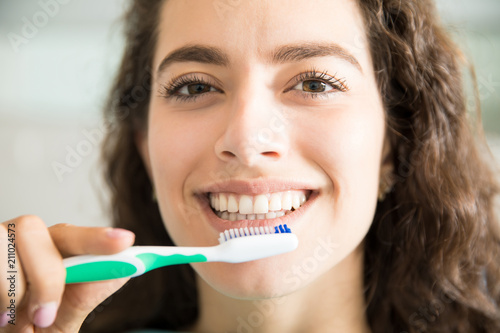 Beautiful Woman Brushing Teeth In Dental Clinic