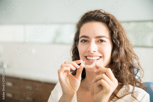Fototapeta Naklejka Na Ścianę i Meble -  Beautiful Patient Holding Orthodontic Retainers In Dental Clinic