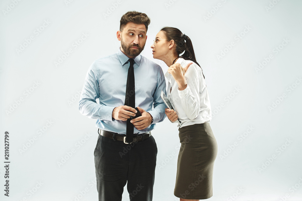 The young woman whispering a secret behind her hand over white background The young woman whispering a secret behind her hand over white background