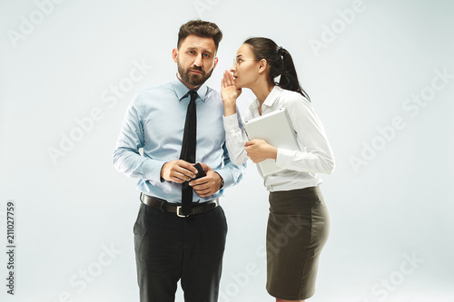 The young woman whispering a secret behind her hand over white background