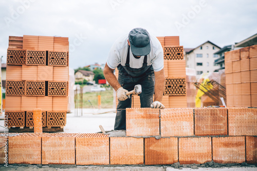 Close up details of industrial bricklayer installing bricks on construction site. photo