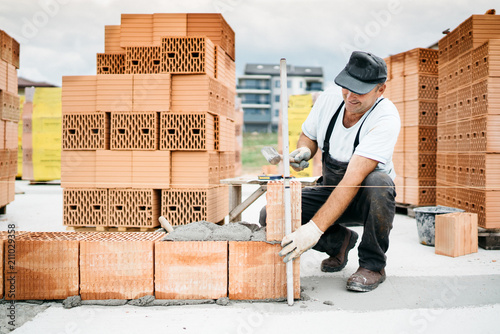 Obraz na płótnie construction worker building walls and working with bricks on construction site