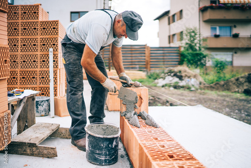 Construction industry details - Worker mason building exterior brick walls photo