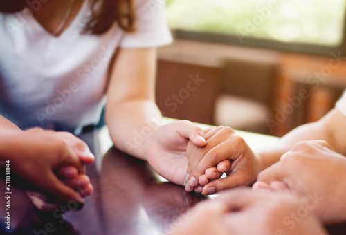 Group of people holding hands and praying.