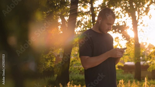 man with a phone and wireless headphones in the park photo