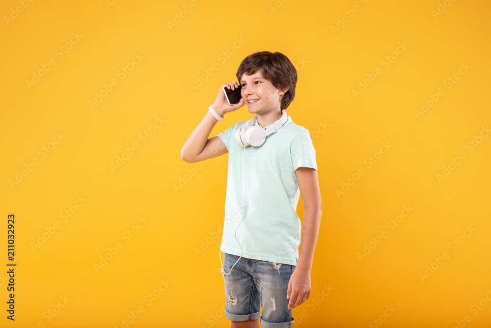 Nice talk. Happy dark-haired boy smiling while talking on the phone Nice talk. Happy dark-haired boy smiling while talking on the phone