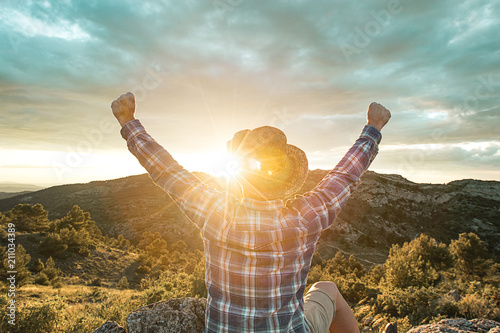 Photos Man at sunset in the mountains with his arms raised
