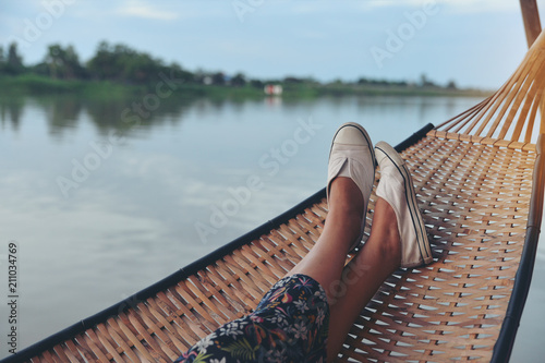 Lifestyle of alone woman, feet of Hipster calm people sleeping and relaxing in hammock with nature background. Lifestyle and relaxing Concept. #211034769