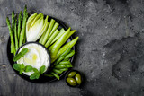 Green vegetables snack board with yogurt sauce or labneh dip. Healthy raw summer platter. Copy space
