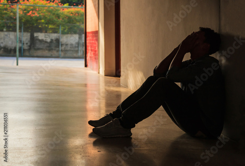 Emotional moment: man sitting holding face in hands, stressed sad young male having mental problems, feeling bad, depressed, disappointed, hopeless. Desperate man in the dark corner needing help.