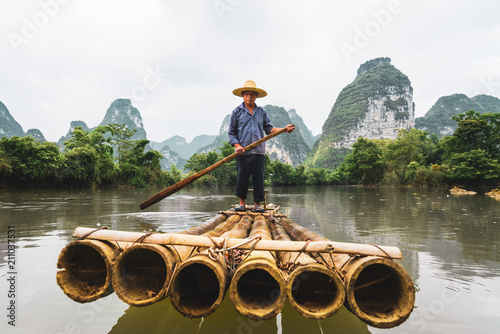 Portrait of man standing on bamboo raft in Quay Son River photo
