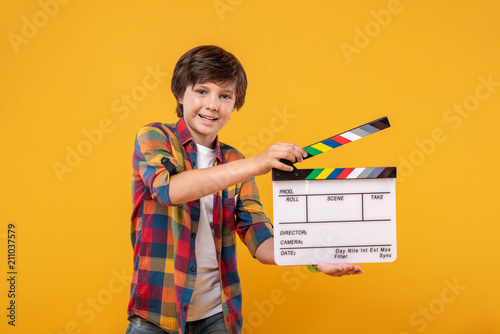 I love shooting. Content dark-haired boy smiling and holding a table