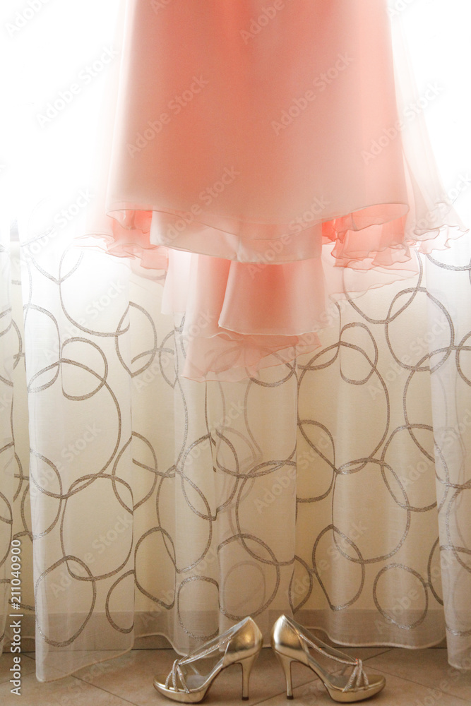 Scarpe décolleté dorate e abito da sposa rosa, appeso sulla tenda di una  finestra foto de Stock | Adobe Stock