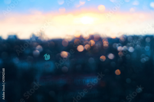 Rain drops texture on window glass with stunning vintage blue violet sunset light abstract blurred cityscape skyline bokeh background. Soft focus.