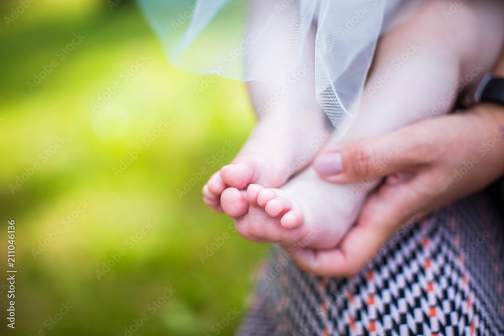 Naklejka premium Little baby legs on the mother's palm, newborn