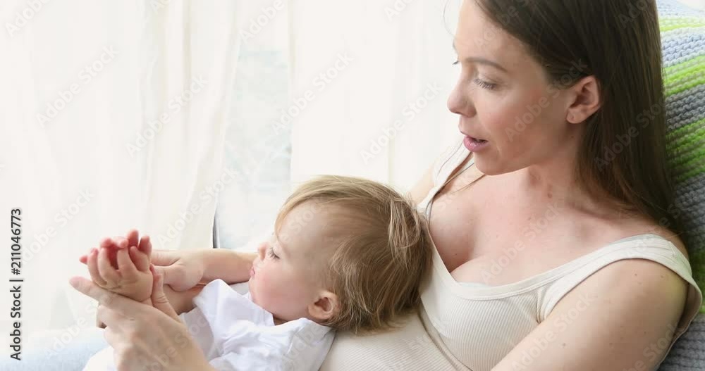 Pregnant woman sitting in armchair with little son and doing finger exercises in daylight Pregnant woman sitting in armchair with little son and doing finger exercises in daylight