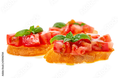 Italian traditional bruschetta with toasted baguette, chopped tomato, green leaf of basil and olive oil isolated on white background, close up