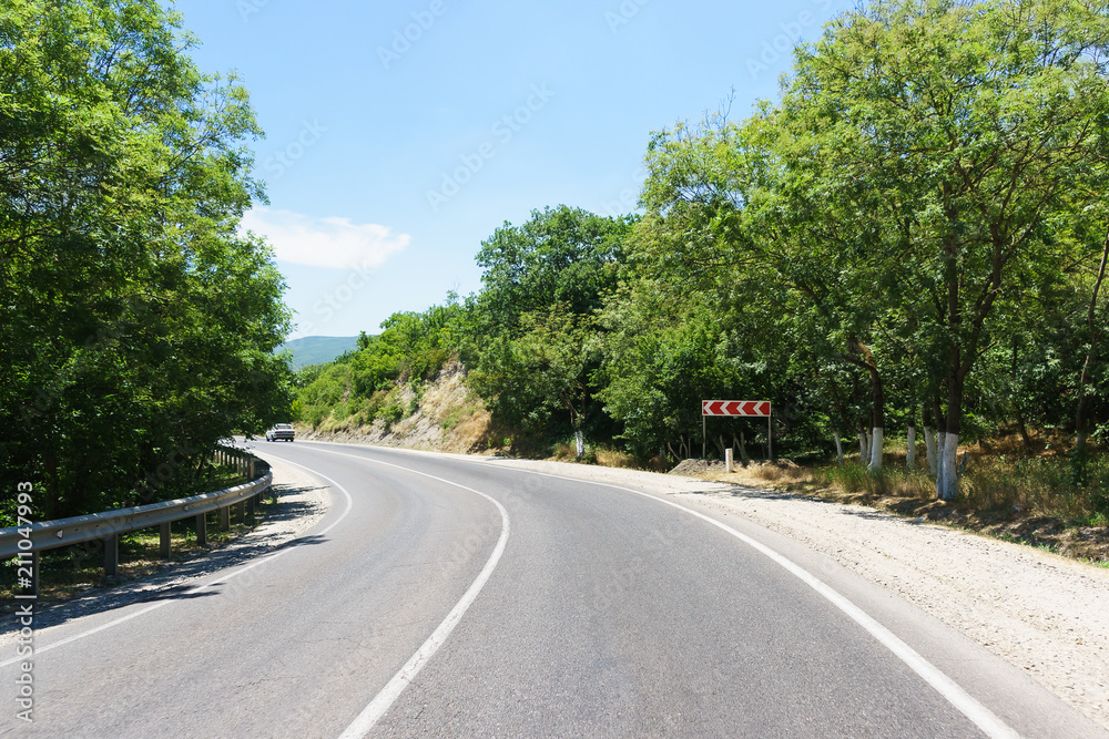 Turn a two-lane road in the mountains. Red sign direction of turn