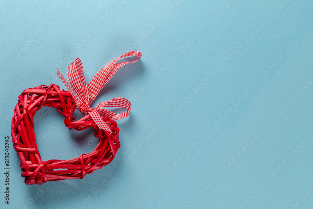Red woven straw heart on blue background. Symbol of love or health Red woven straw heart on blue background. Symbol of love or health