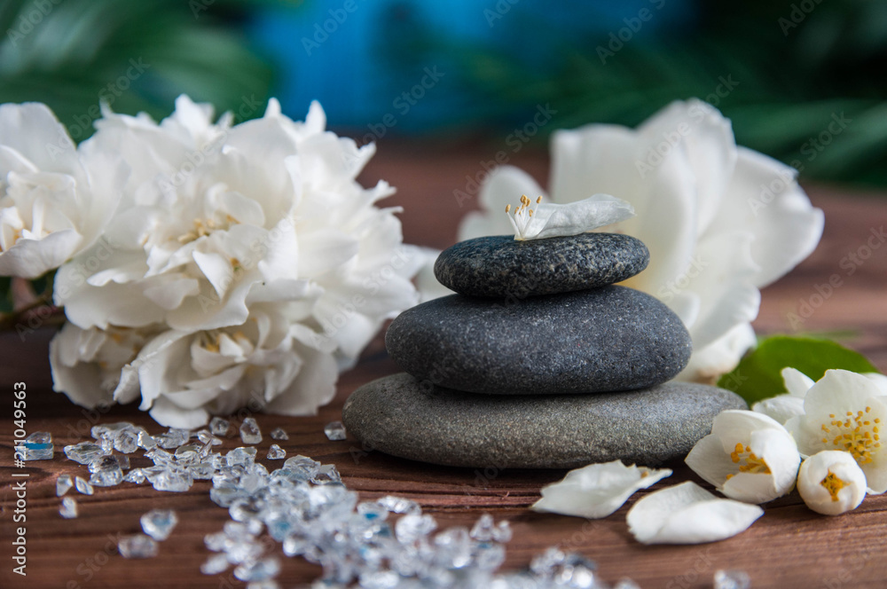 Fototapeta premium Pyramids of gray zen stones with beautiful fresh white flowers. Concept of harmony, balance and meditation, spa, massage, relax