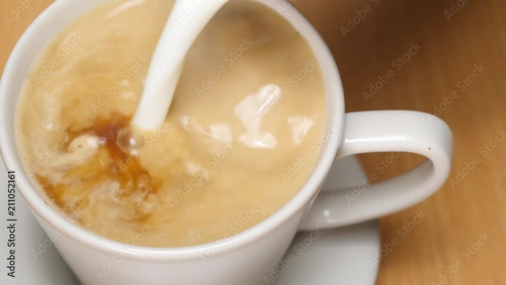 Pouring stream milk into cup of espresso, slow motion Pouring stream milk into cup of espresso, slow motion