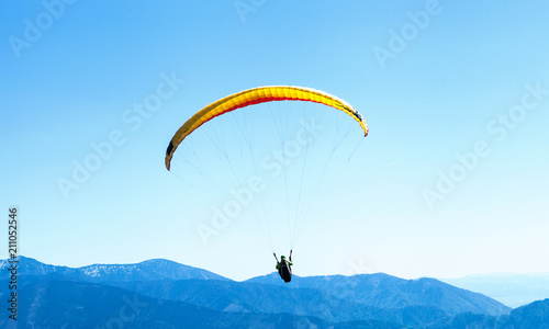 Paraglider soaring in the sky over the blue mountains