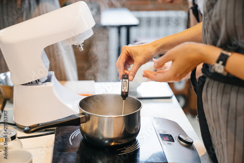 Photography The cook measures the temperature of the liquid in a saucepan on the oven using a special device, electronic thermometer