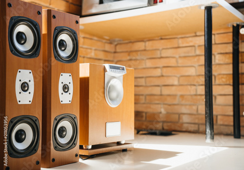 Wooden Music speakers and a subwoofer in the interior of a light room or office. Musical concept.