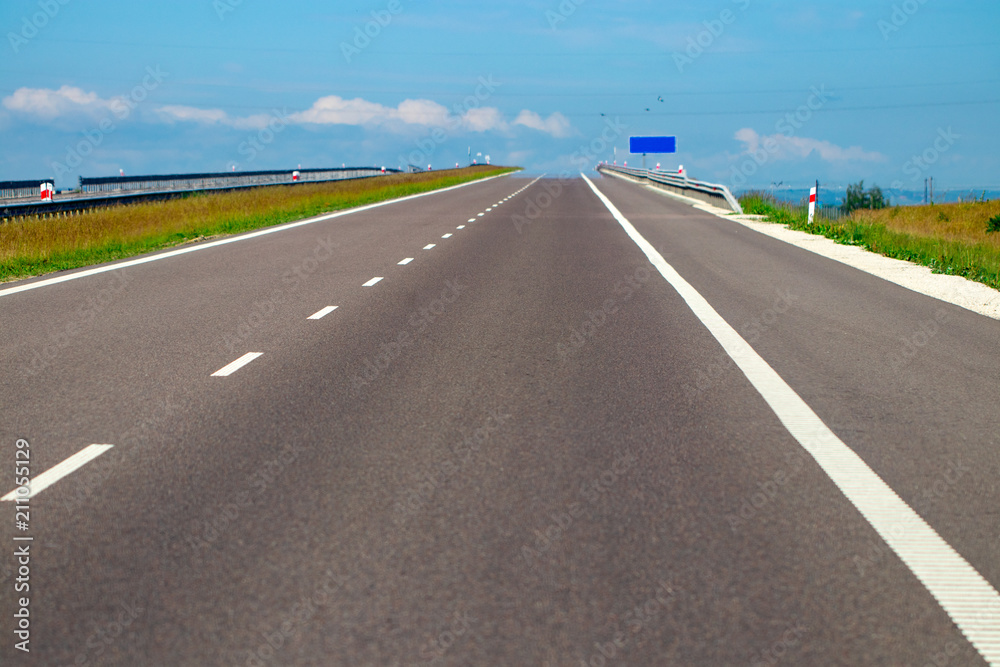 Fototapeta premium empty asphalt road and field and blue sky with clouds