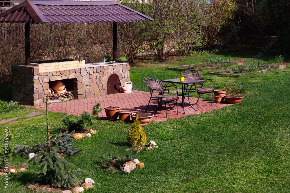 Backyard Patio Area with Fireplace and Furniture.Green Party area. Barbacue Area. Stone.