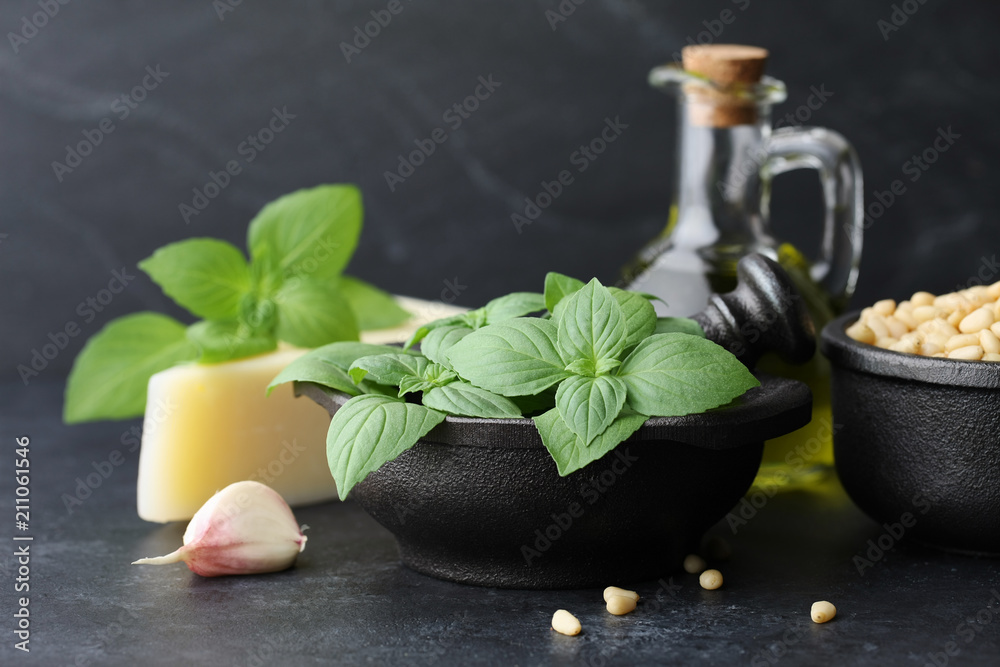 Basil leaves, parmesan cheese, pine nuts, garlic and olive oil on black stone background. Pesto sauce ingredients. Basil leaves, parmesan cheese, pine nuts, garlic and olive oil on black stone background. Pesto sauce ingredients.