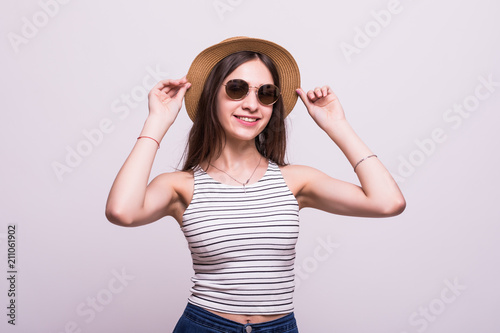 Portrait of a smiling attractive woman in summer dress and hat posing while standing and looking at camera isolated over white background
